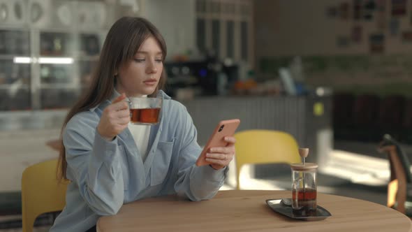 Caucasian Woman Drinking Tea and Using Smartphone