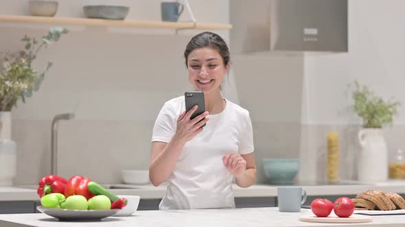 Indian Woman Doing Video Call on Smartphone in Kitchen