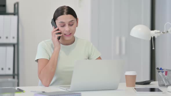 Young Latin Woman Talking on Phone at Work