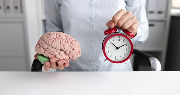 Woman Stretches Forward a Mock Up of Human Brain and Alarm Clock