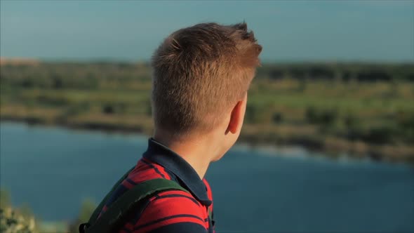 Close Up Portrait Caucasian Boy Teenager in a Red Shirt with a Backpack on His Back, at Sunset