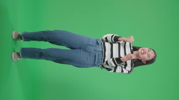 Full Body Of A Happy Asian Woman Celebrating While Standing In Front Of Green Screen Background