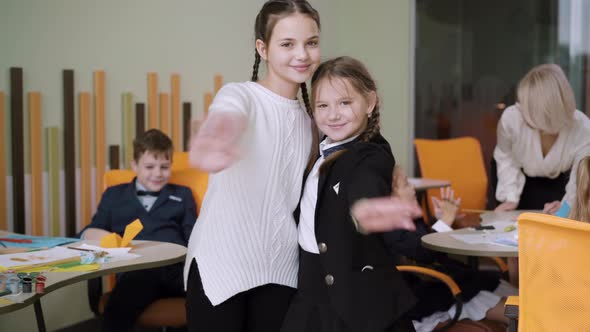 Portrait of Beautiful Positive Classmates Hugging and Waving at Camera