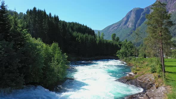 Huge turquoise crispy glacial river flowing down from lake Lovatnet Norway - Melted glacier ice from