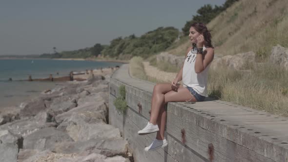 Young Attractive Woman Listening To Music On Head Phones At The Beach - Ungraded