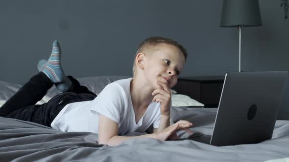 A Small Child Uses A Computer, Looks at The Laptop Screen, Watches Videos or Cartoons