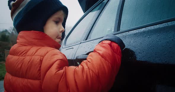 Cute Child Drawing on the Wet Car After Rain