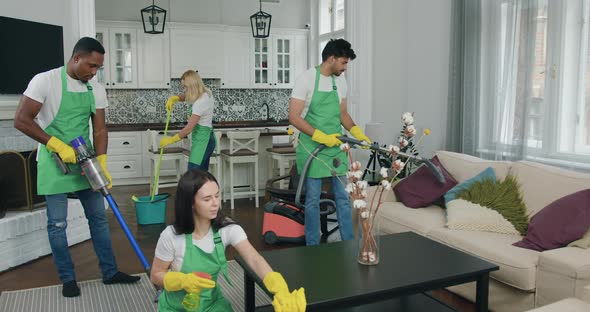 Diverse Workers from Cleaning Company Cleaning up Contemporary flat with Vacuums