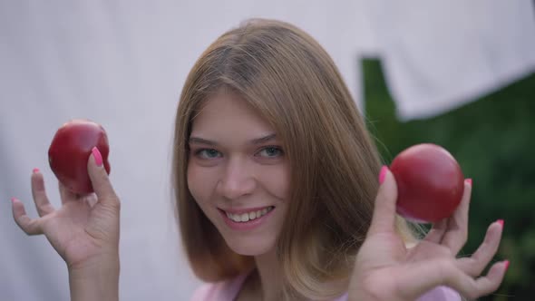 Joyful Young Woman Having Fun Posing with Red Tomatos Outdoors Smiling