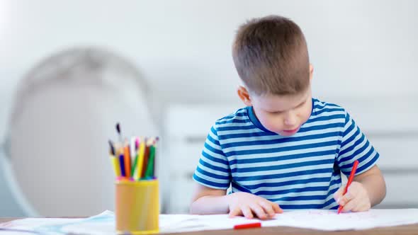 Enthusiastic Little Boy Writing on Paper Using Colorful Pencil at Classroom Medium Shot