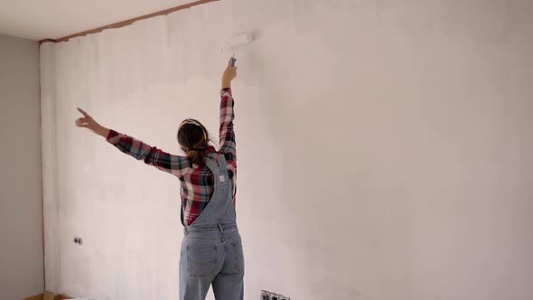 Excited Joyful Lady Sing Dancing Against Half Colored Wall at New Flat After Relocation