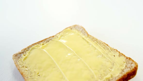 Butter spread on bread slice against white background
