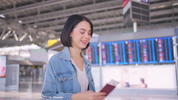 Asian young attractive woman passenger walking in airport terminal to boarding gate to airplane.