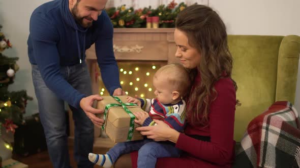 Mother, Father and Little Baby Sitting Near Decorated Christmas Tree