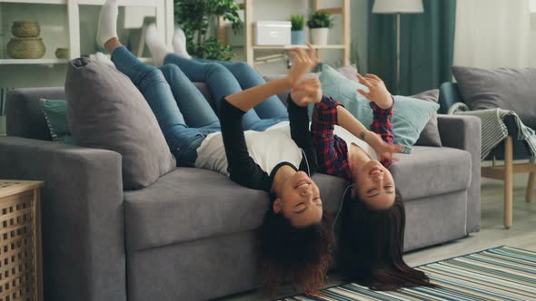 Joyful Young Ladies Are Having Fun Together at Home Listening To Music with Smartphone and Earphones