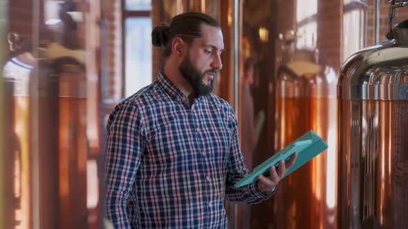 Confident Man Standing in Brewery with Tablet Checking Online Orders for Highquality Beer