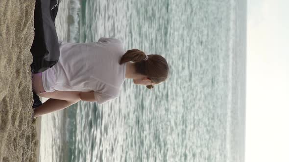 Girl Sitting By the Sea on the Sand Vertical Video