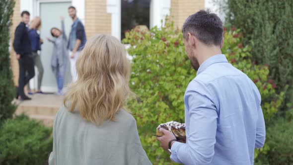 Mature Caucasian Couple Smiling at Camera, Turning Back and Walking To the Group of People