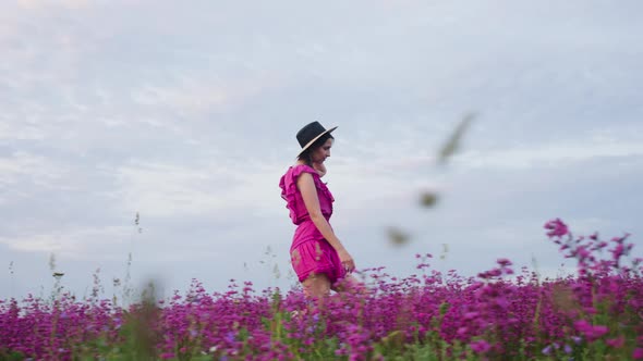 Girl in a Straw Hat and a Short Dress Walks on a Field