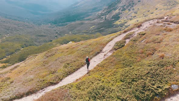 Aerial View of a Traveler with Backpack Climbing Along Mountain Slope. Epic Shot