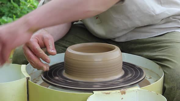 Male Potter of Caucasian Ethnicity in Working Uniform Makes a Clay Pot Closeup