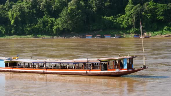 Long-tail boat moving at the current at the Mekong river in Luang Prabang