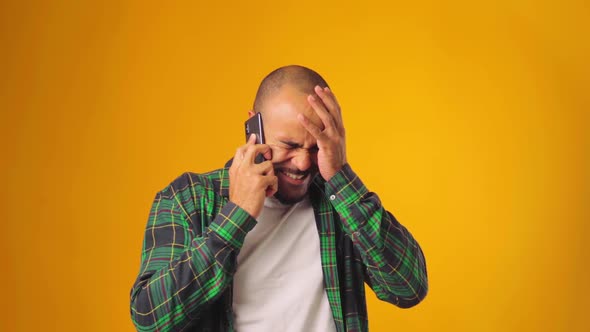 Irritated Displeased African American Young Man Talking on the Phone Against Yellow Background