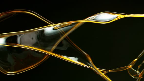 Super Slow Motion Shot of Swirling and Splashing Golden Oil on Black Background at 1000Fps