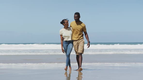 Happy african american couple hugging each other and walking at the beach