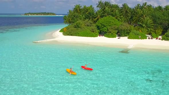 Aerial drone view of a man and woman couple kayaking around a tropical island