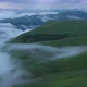 Aerial view on the  green fields at the mountains in the clouds and fog - VideoHive Item for Sale