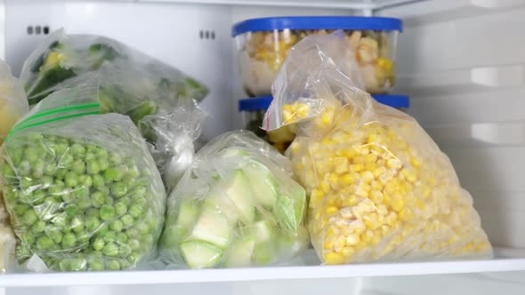 Female Hands pulls frozen corn out of the fridge. Frozen fruits, vegetables, meat in the freezer.