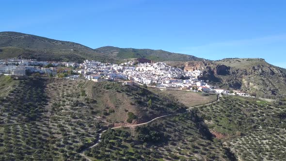 Aerial view of a traditional spanish white village in the mountains with a big church.