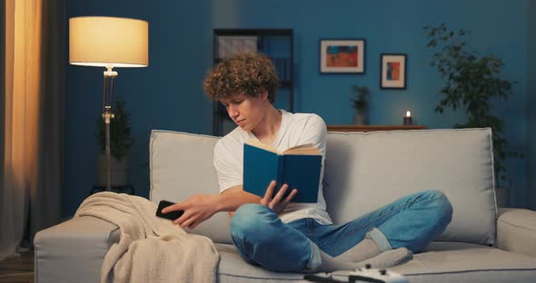 A Young Teenage Boy Relaxes on the Couch Reading a School Book the Book Bores alt