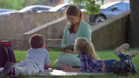 Extracurricular Activities, Cute Kids Listening To Woman Reading Book After School Sitting on Green