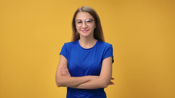 Portrait of Smiling Beautiful Woman Posing Standing with Crossed Hands Isolated on Orange Studio