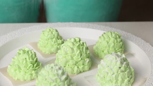 A Woman Sprinkles Powdered Sugar On Marshmallow Cones. Light Green Marshmallow Cones. Close Up Shot.