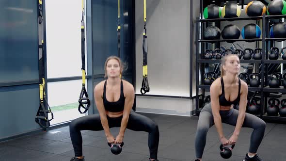 Young Women Doing Exercise with Kettlebells
