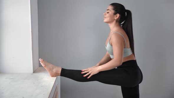 Active Young Woman Performing Flexibility Stretching Leg on Windowsill Enjoying Healthy Lifestyle