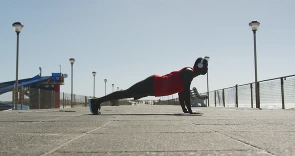 Focused african american man doing press ups, exercising outdoors by the seaside