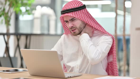 Stressed Arab Businessman with Laptop Having Neck Pain in Office 