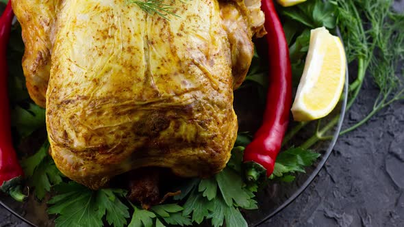 a Whole Baked Chicken Lies in a Plate with Red Chili and Dill with Parsley Slow Motion