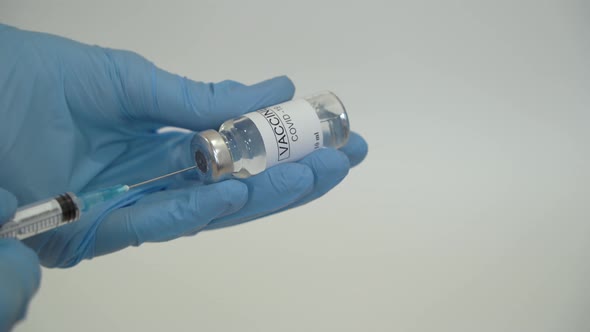 Doctor draws coronavirus vaccine into a syringe.