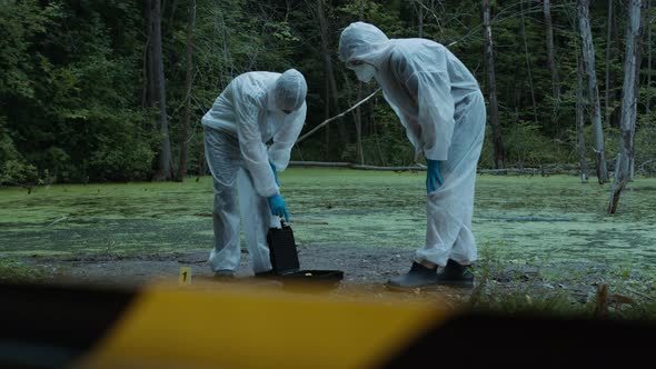 Criminalists Working with Knife at Crime Scene Territory Closed with Signal Tape