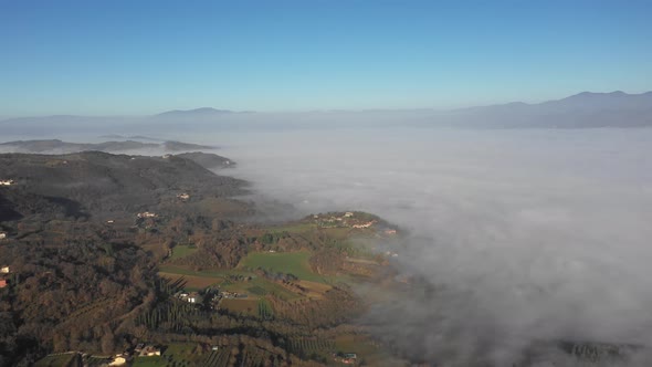 Aerial view of morning fog over forest and village in Umbria, Italy