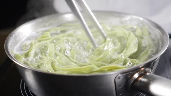 Cooking and Stirring Spaghetti with Creamy Sauce in Frying Pan, Close-up Shot. Food Video in Slow