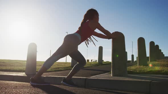 African american woman in sportswear stretching in street before exercising