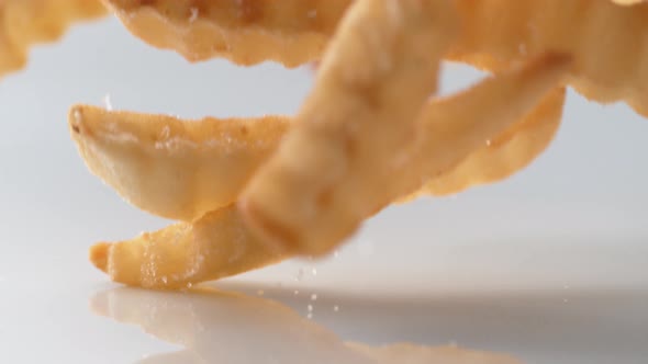 French fries falling on white surface. Slow Motion.