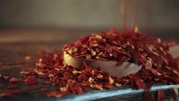 Flakes of Red Hot Chili Pepper in Wooden Spoon Closeup on a Kitchen Table