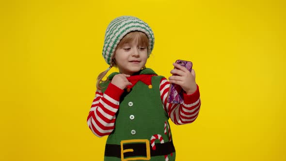 Kid Child Girl in Christmas Elf Santa Claus Helper Costume Making a Video Call on Mobile Phone